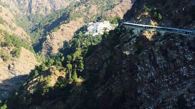 A cable car bridge over a valley with mountains in the background.