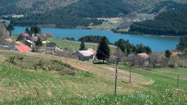 A lake surrounded by hills, houses, and a clear sky.