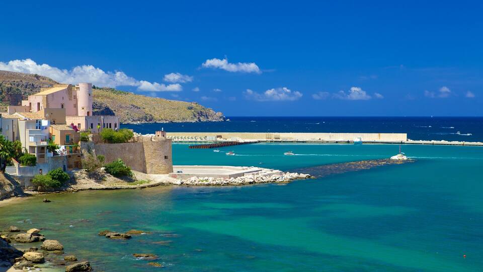 A coastal town with buildings, a fort, and a clear blue sea.