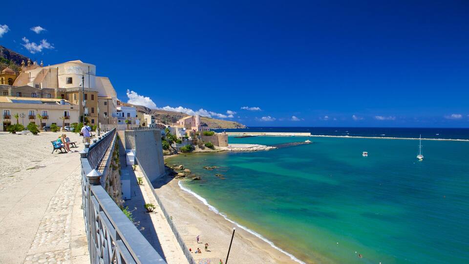 A coastal town with buildings, a beach, and clear blue waters.
