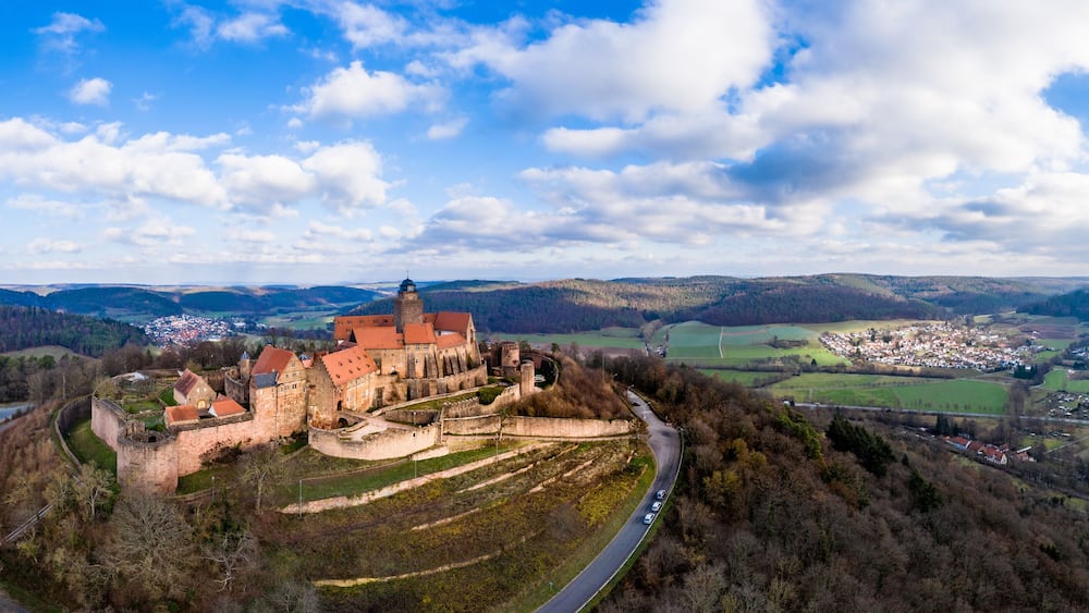 A historic castle surrounded by a moat, with a town in the background.