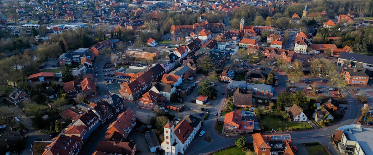 An aerial view of a town with red-roofed houses, a church, and a mix of residential and commercial buildings.