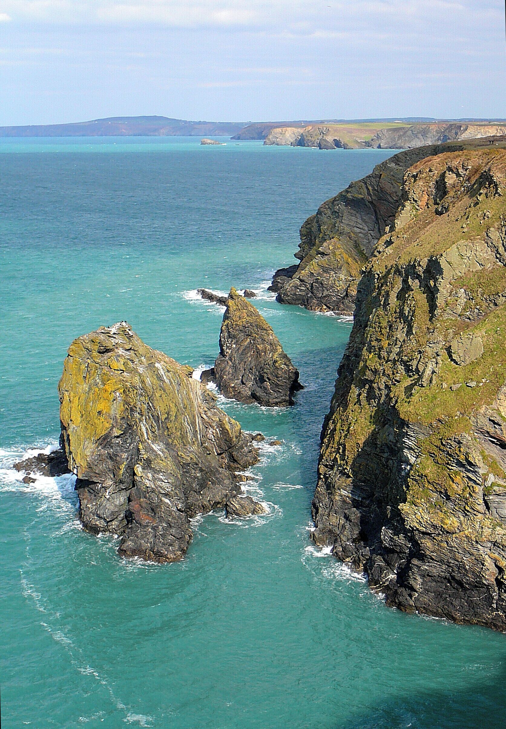 A coastal landscape with rocky cliffs and turquoise sea.