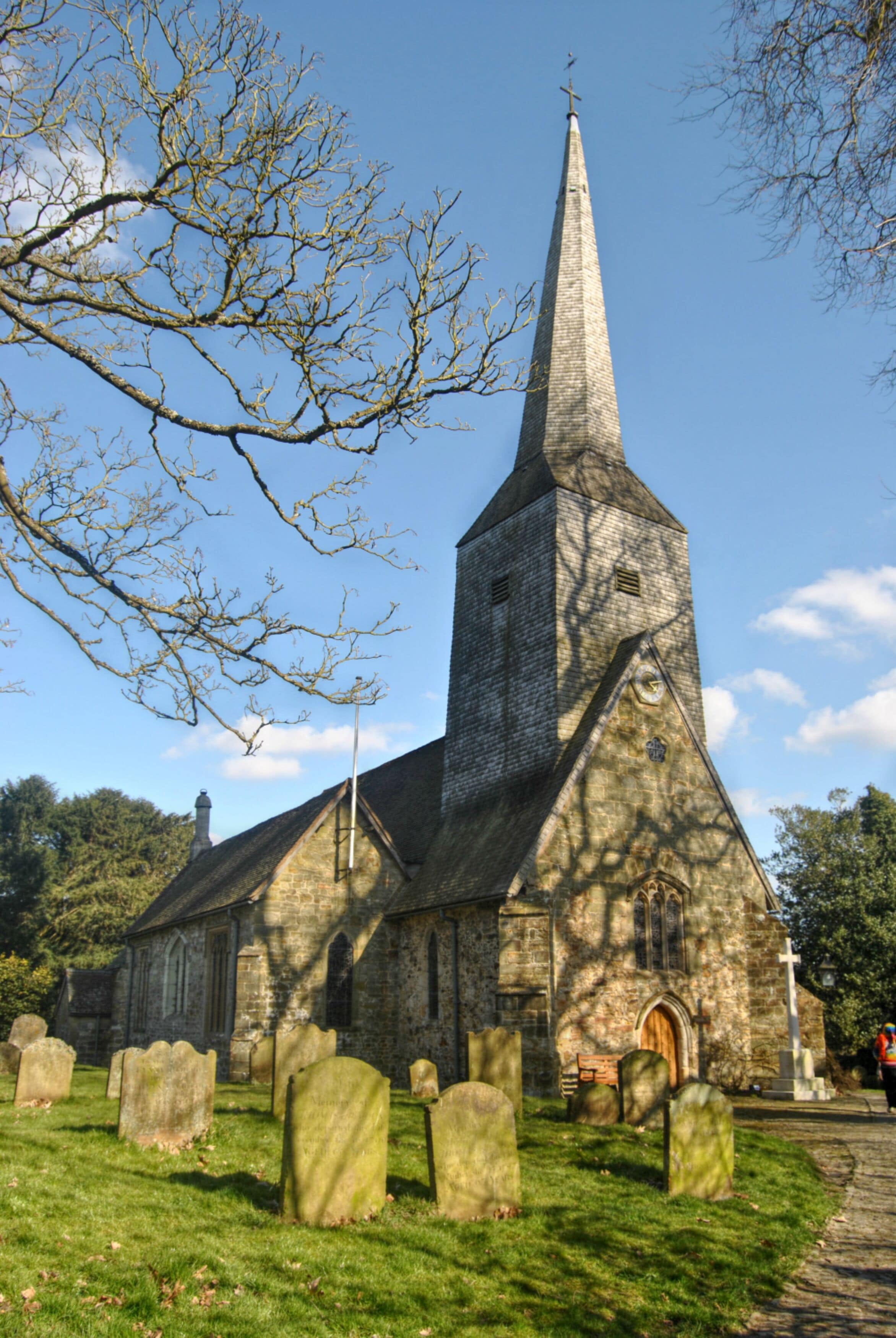 A church with a tall steeple and a graveyard in front.