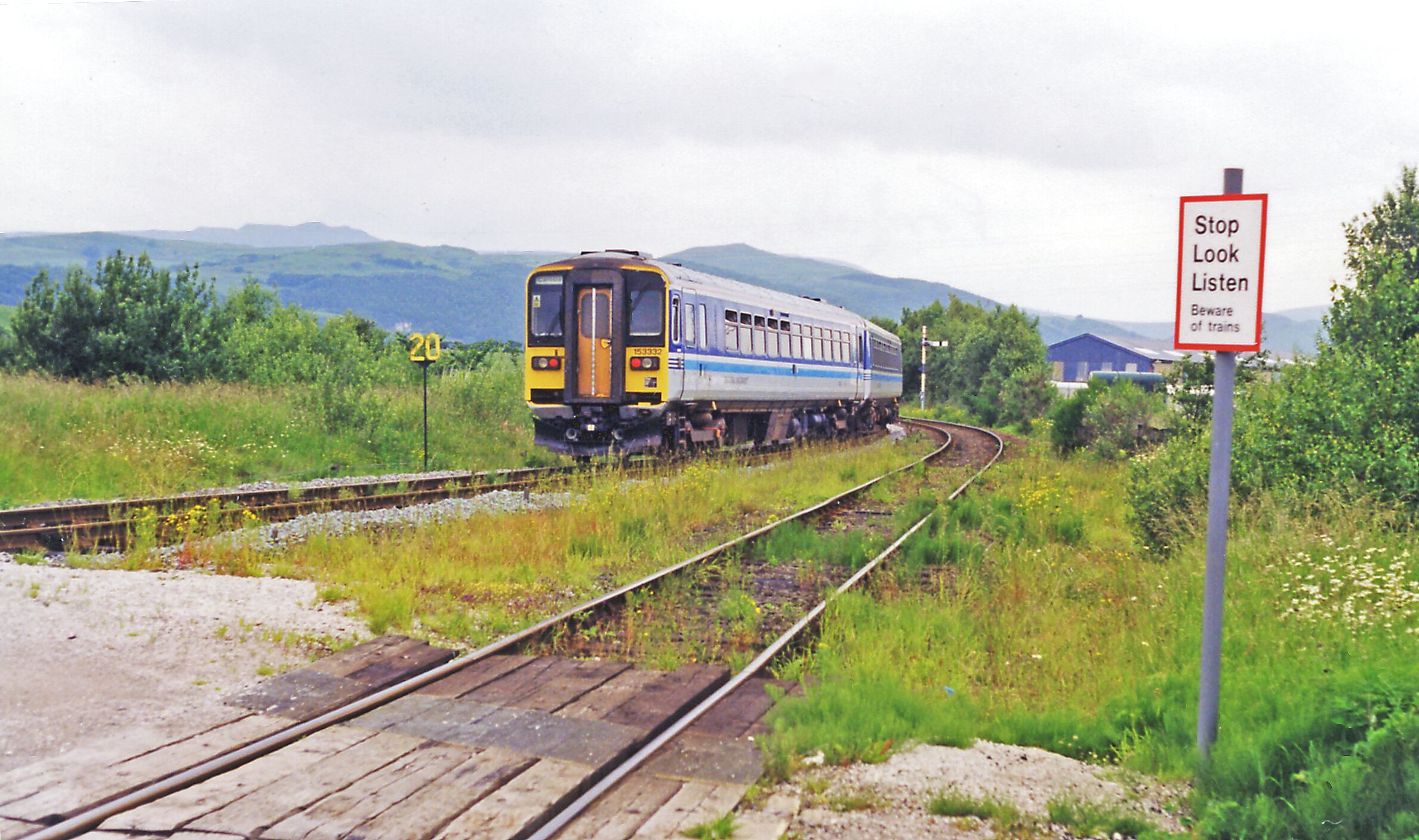 A train on railway tracks with a sign that reads "Stop Look Listen Beware of trains".