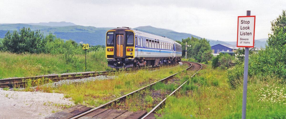A train on railway tracks with a sign that reads "Stop Look Listen Beware of trains".