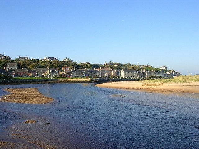 A river with a sandy beach and houses along the riverbank.