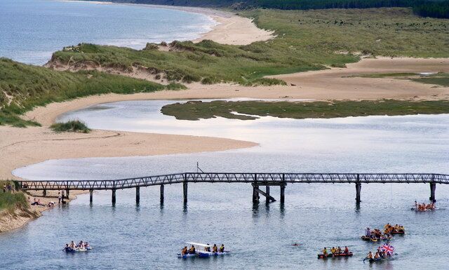 A river with a bridge, boats, and a beach.