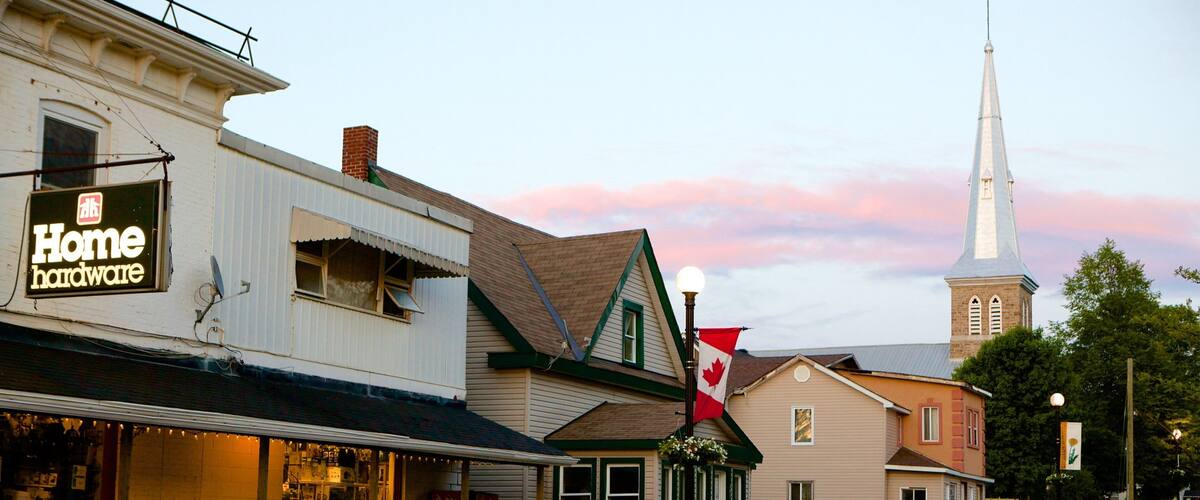 A street with a church steeple, a Home hardware store, and a Coca-Cola sign.