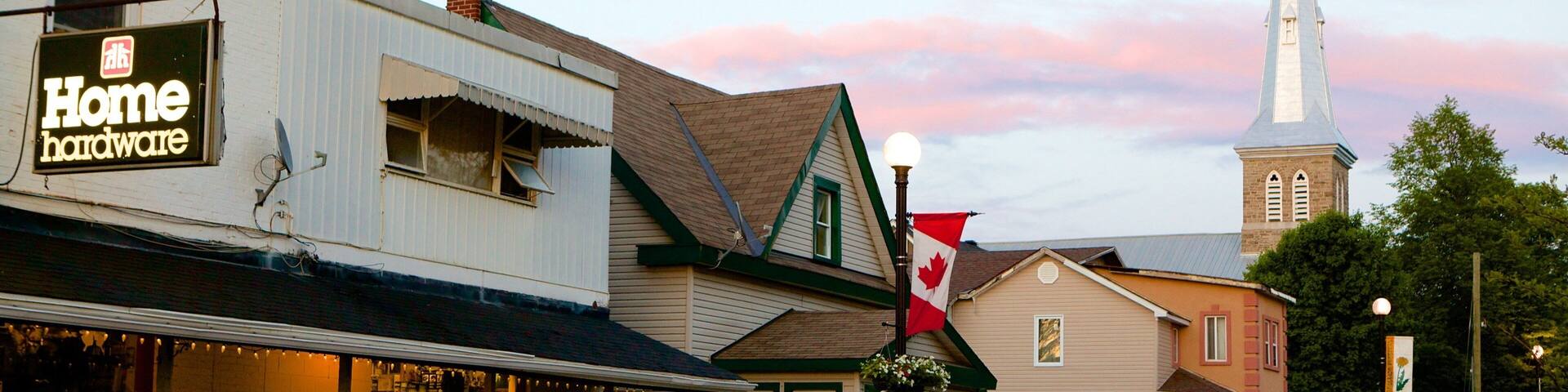A street with a church steeple, a Home hardware store, and a Coca-Cola sign.