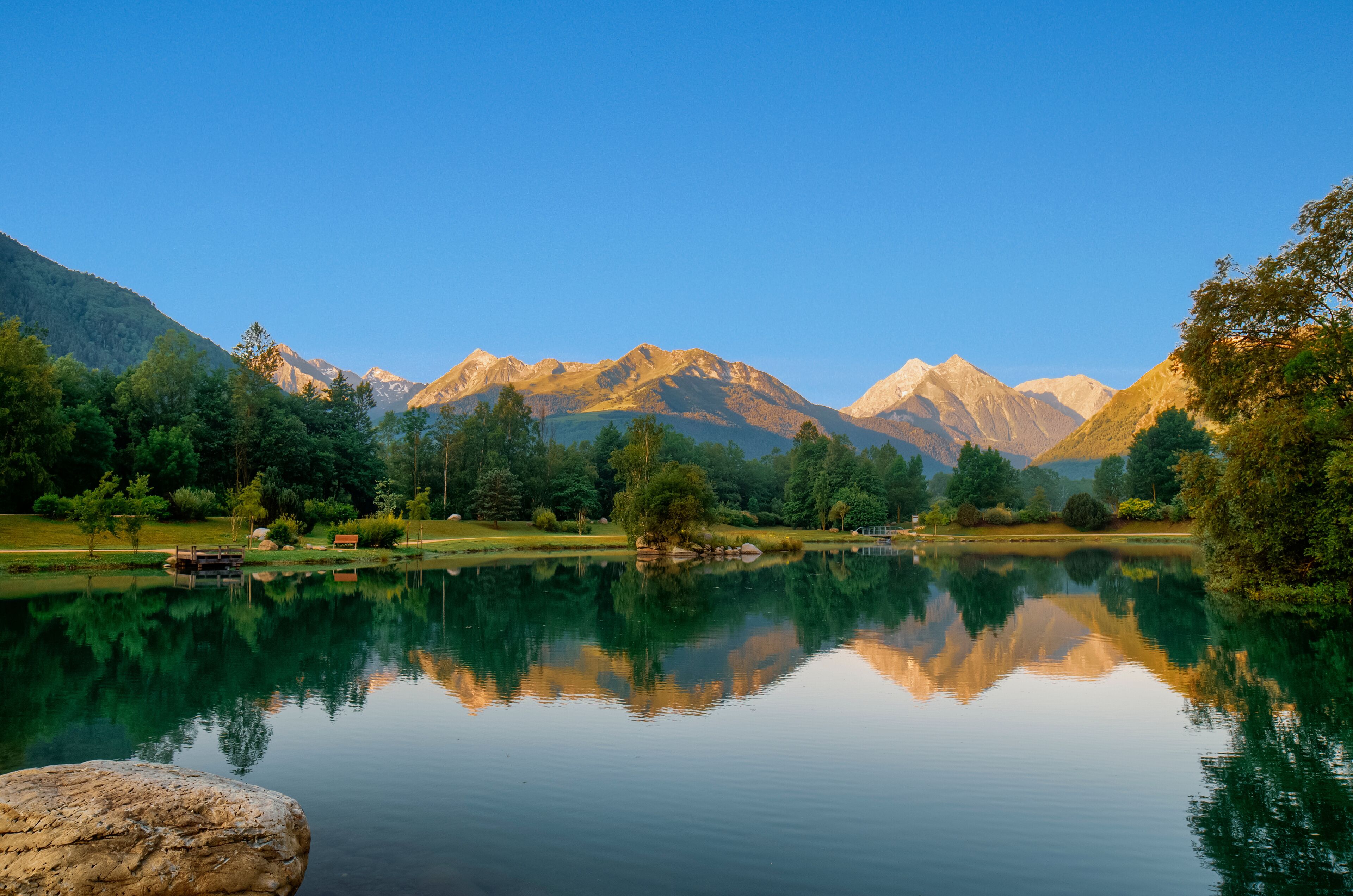 A tranquil lake with clear reflections of surrounding mountains and trees.