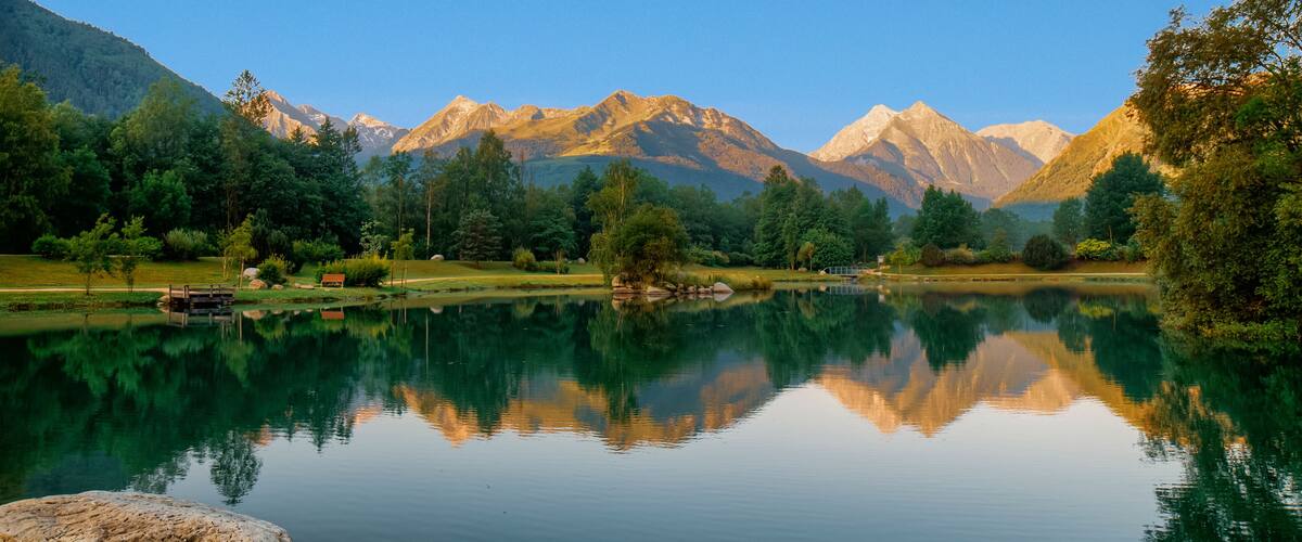 A tranquil lake with clear reflections of surrounding mountains and trees.