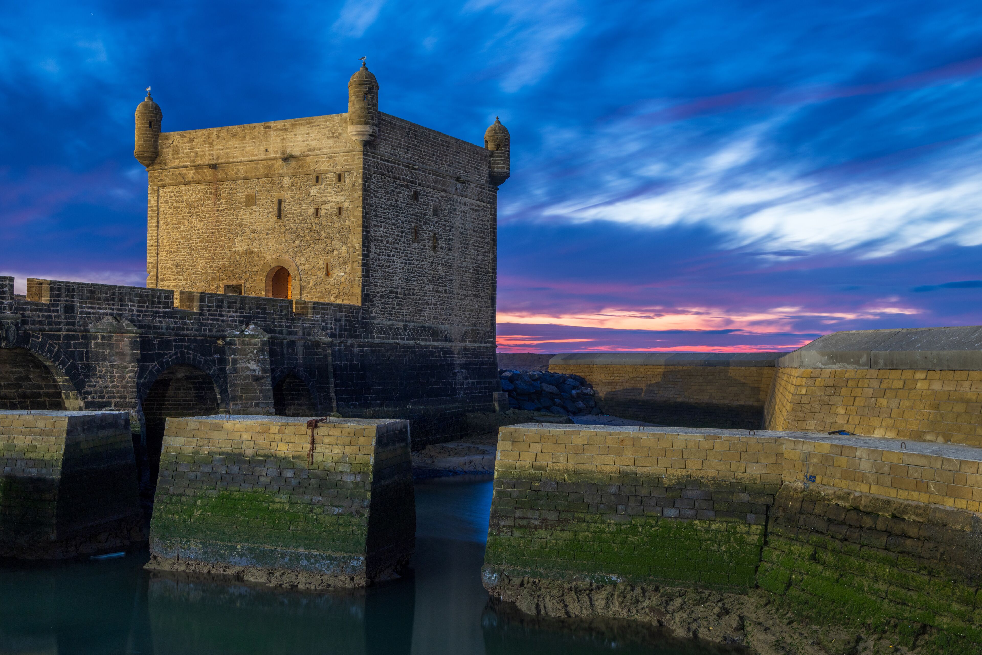 Port of Essaouira Sqala, Portuguese castle in a sunset lights with stone wall and moat in the foreground, Essaouira, Morocco