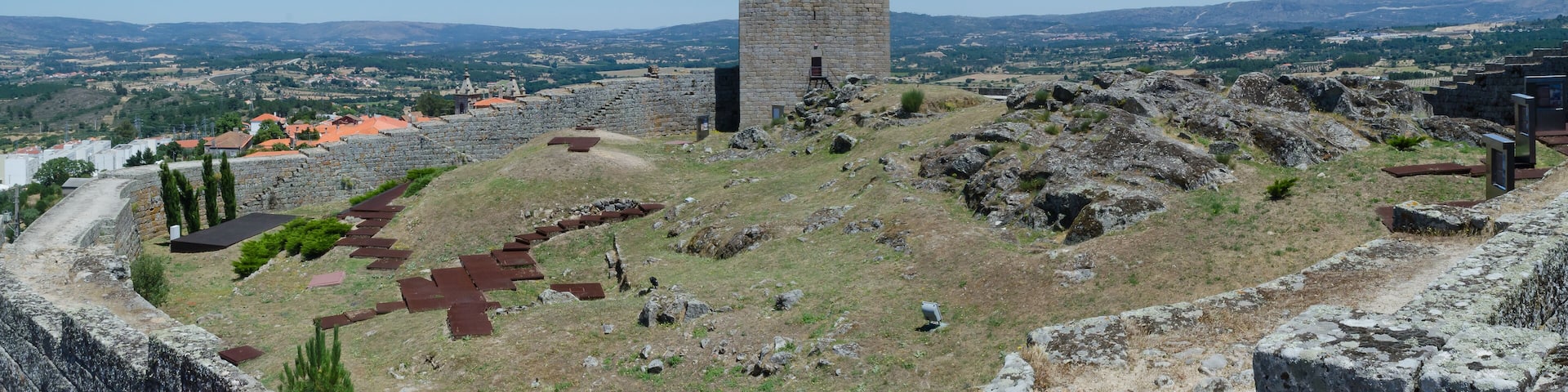 A historic stone tower and ruins on a hill overlooking a town.