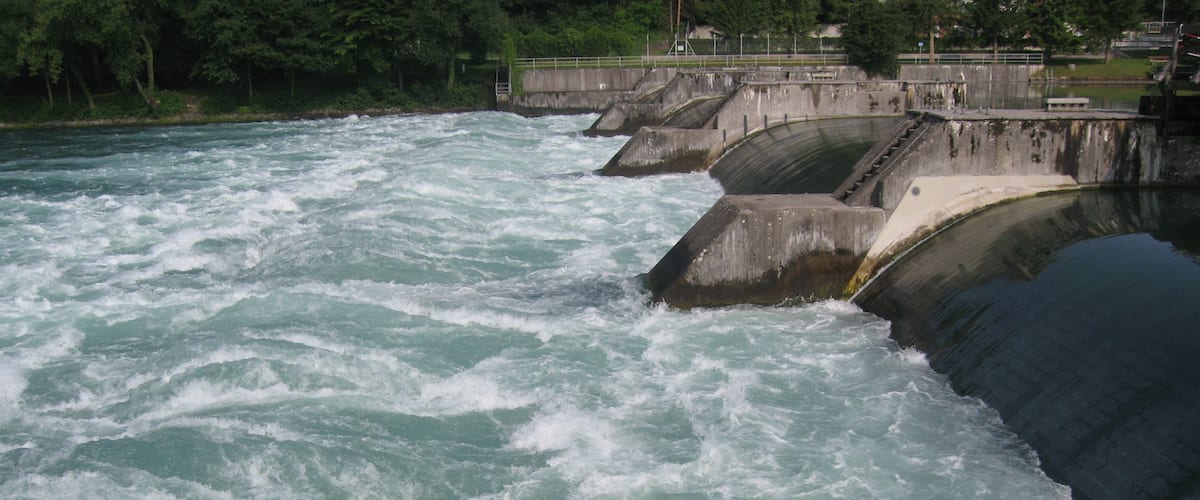 A river with a dam and a swan swimming in the water.
