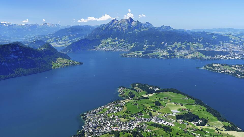 A mountainous landscape with a lake, a town, and a prominent peak.