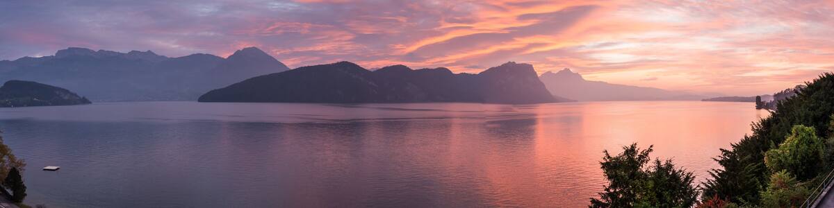 Un lac paisible, avec des montagnes en arrière-plan et un ciel au coucher du soleil aux couleurs vives.