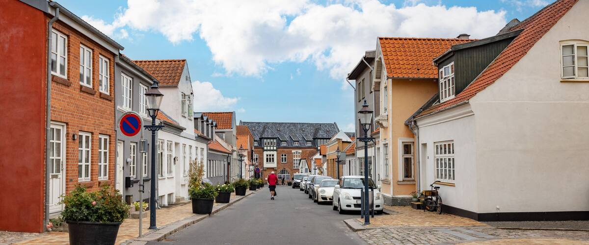 A cobblestone street lined with historic buildings, a no parking sign, and a cyclist in the distance.