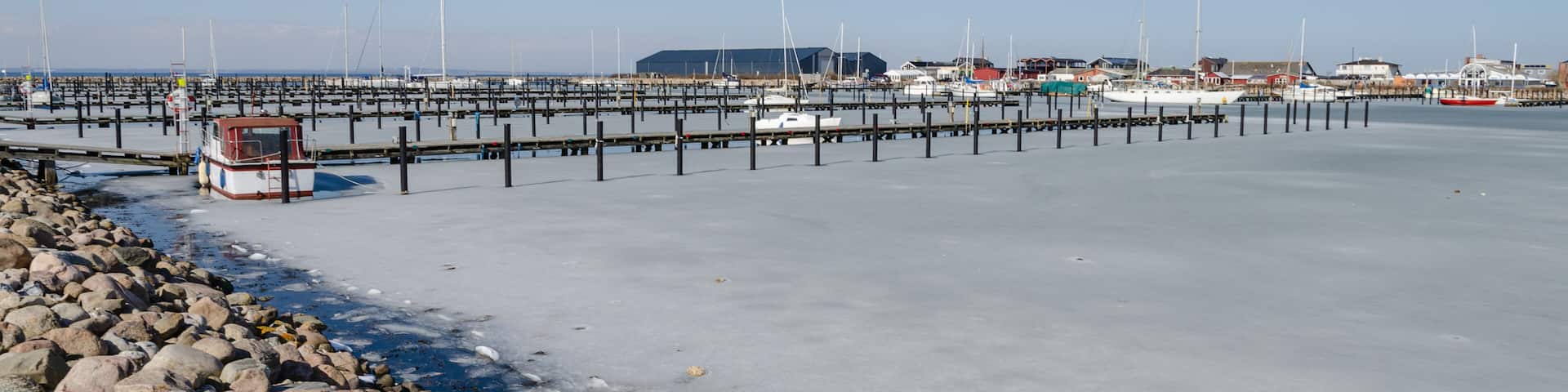 Marina in winter with frozen water and a few boats