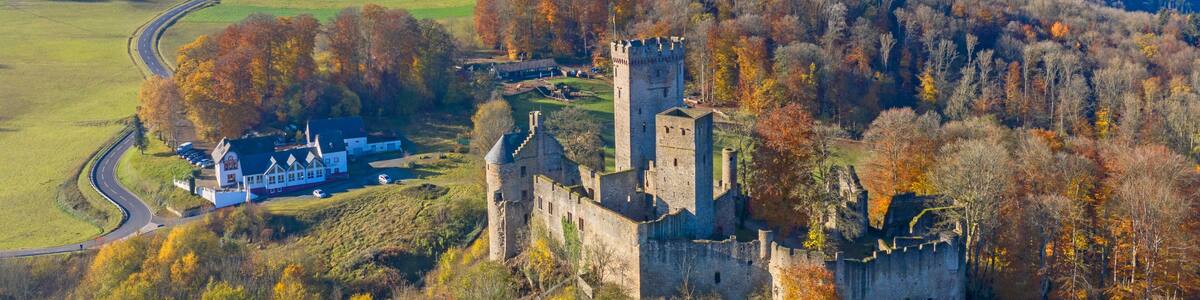 A historic castle surrounded by autumn-colored trees and a rural landscape.