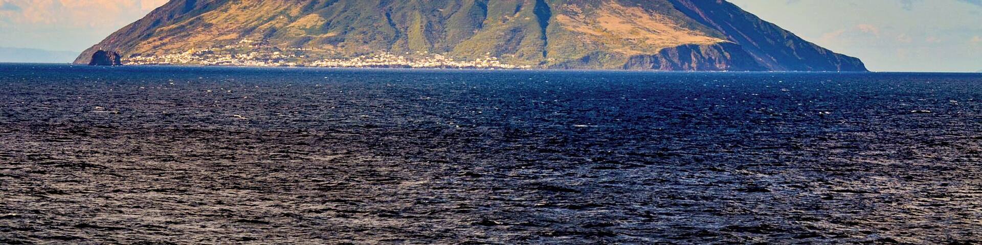 A mountain with a small town at its base, surrounded by the ocean.