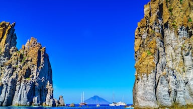 A coastal landscape with towering rock formations and a clear blue sky.
