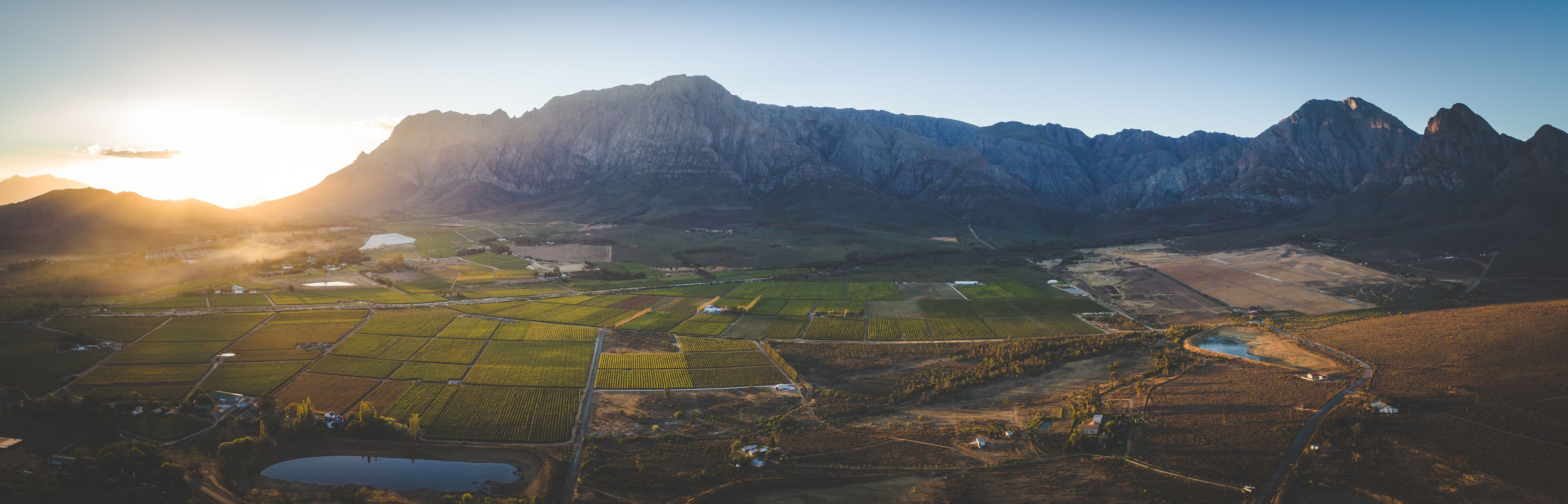 Paisaje montañoso con campos en terrazas y un pequeño cuerpo de agua.