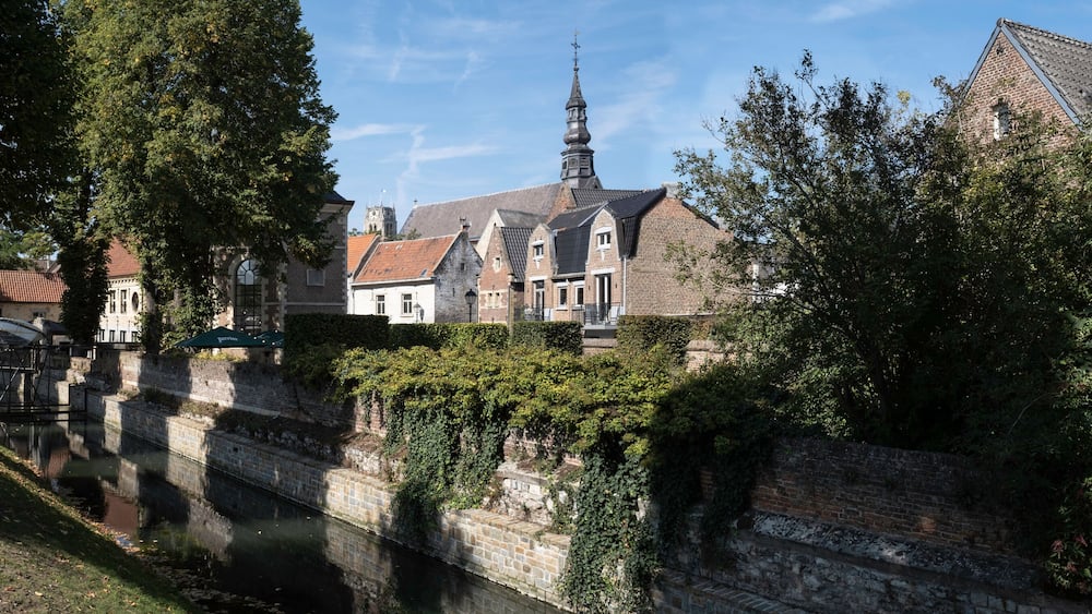 A historic town with a church, a tall tower, and a canal.