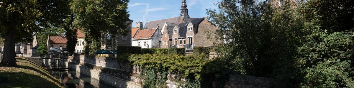 ER 13 2020: Cityscape of Tongeren, the oldest city in Belgium, on the river de Jeker with restored houses and the tower of the Begijnhofkerk in background. Widescreen image