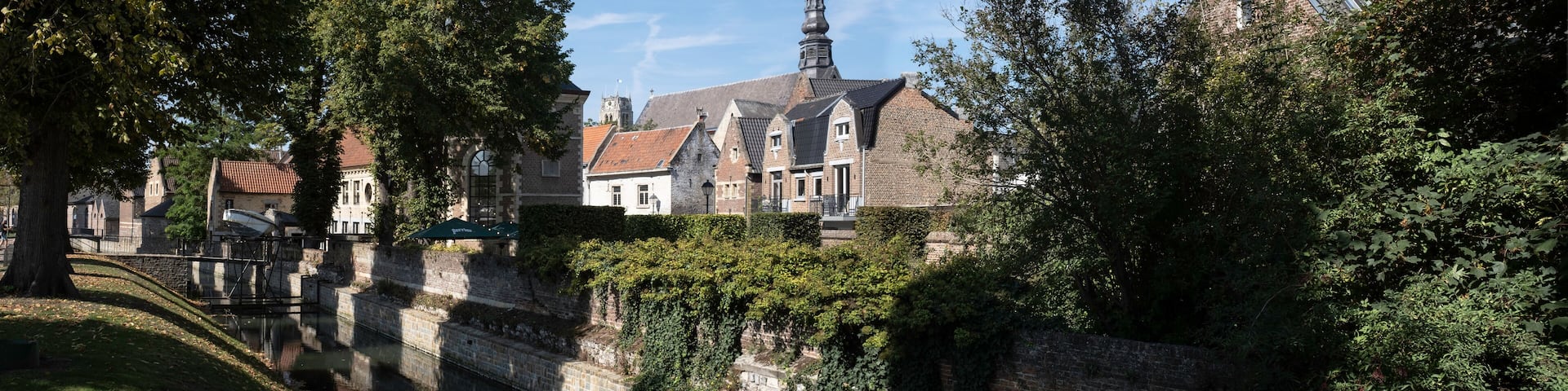 ER 13 2020: Cityscape of Tongeren, the oldest city in Belgium, on the river de Jeker with restored houses and the tower of the Begijnhofkerk in background. Widescreen image