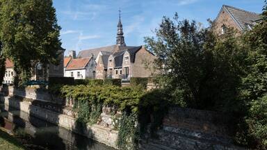 ER 13 2020: Cityscape of Tongeren, the oldest city in Belgium, on the river de Jeker with restored houses and the tower of the Begijnhofkerk in background. Widescreen image