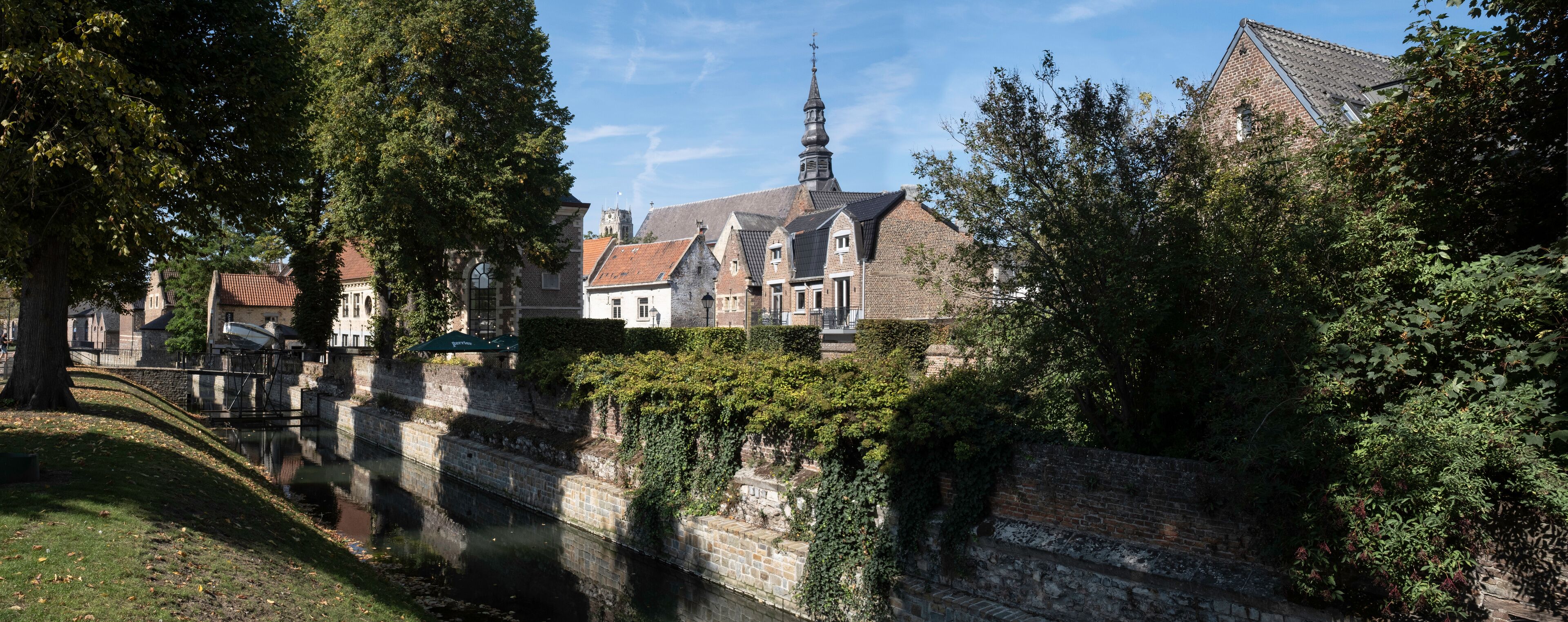 A historic town with a church, a tall tower, and a canal.
