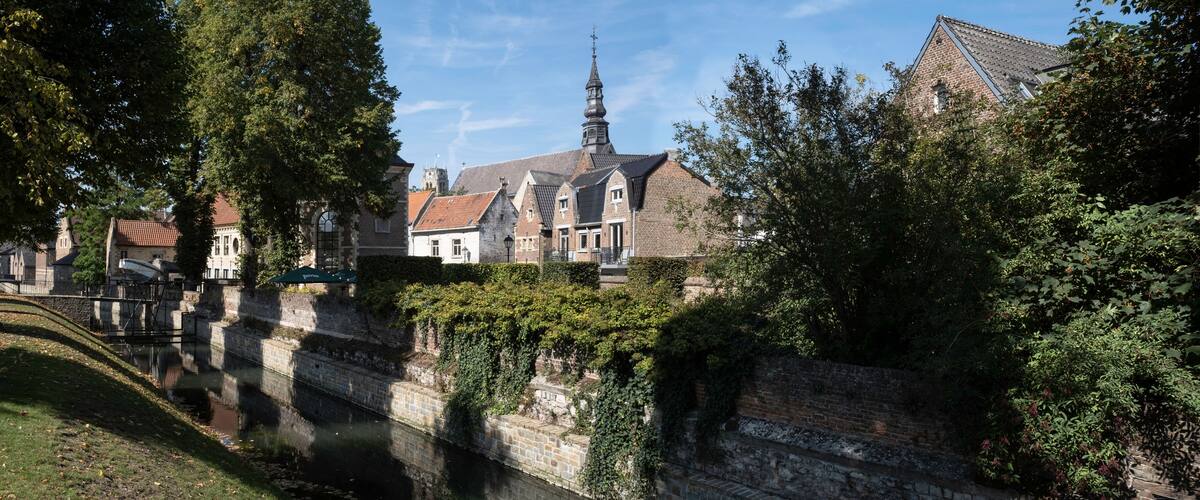 A historic town with a church, a tall tower, and a canal.