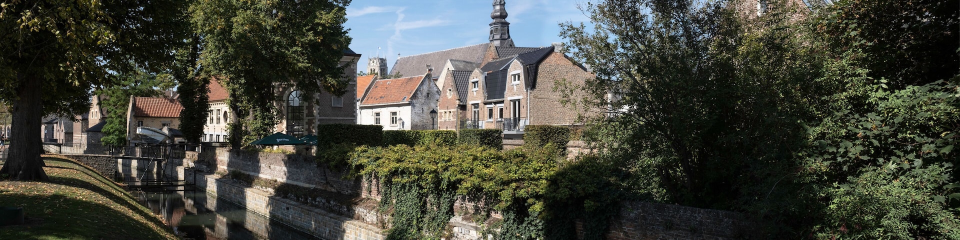 A historic town with a church, a tall tower, and a canal.