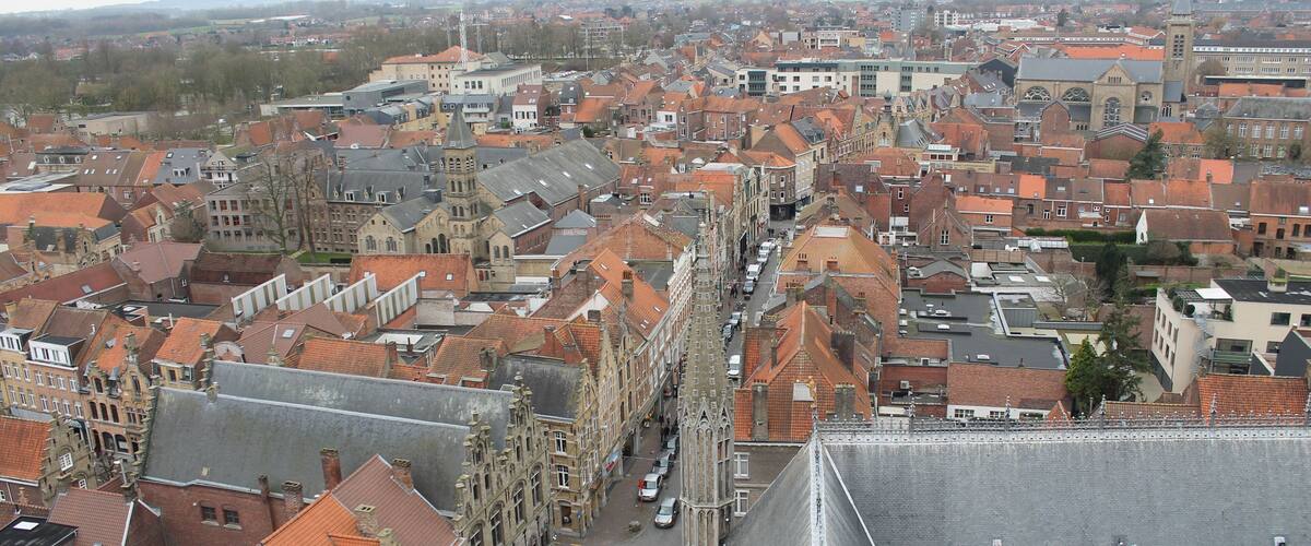 A historic European town with red-tiled roofs, a prominent church, and a steeply sloped building.