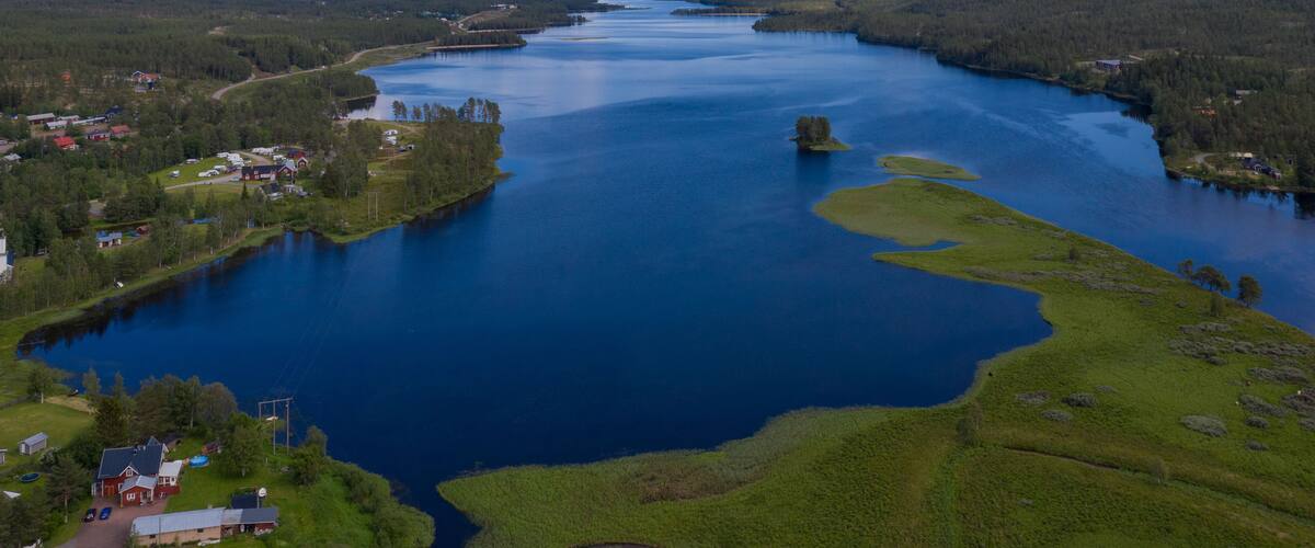 A large lake surrounded by forested hills and small settlements.
