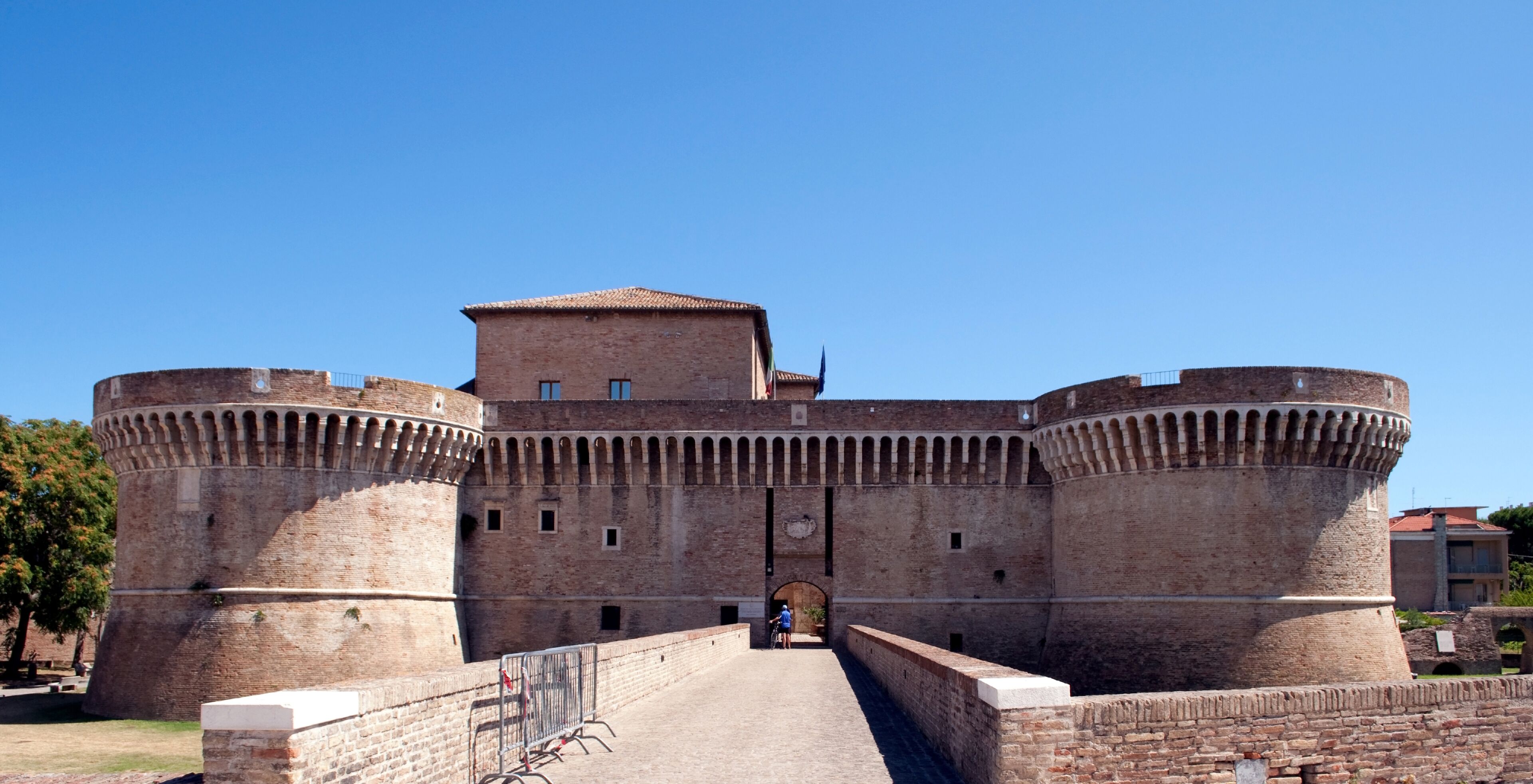 Un castillo de ladrillo histórico con dos torres destacadas y una entrada central.