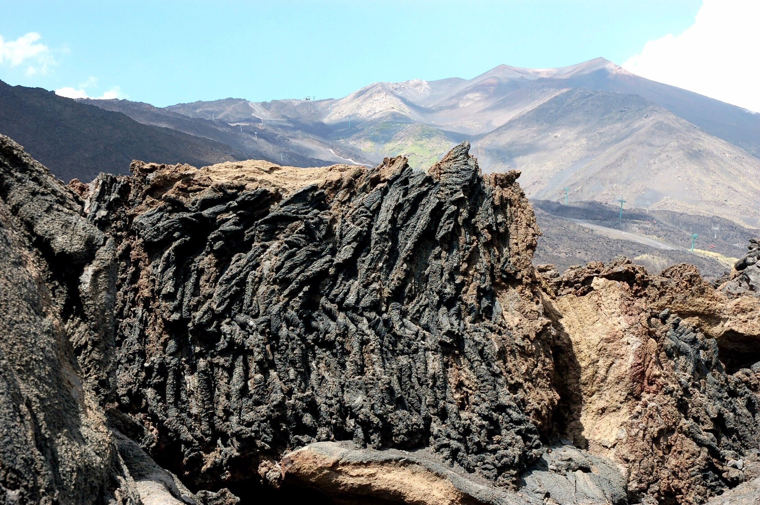 A rugged volcanic landscape with prominent rock formations and distant mountains.