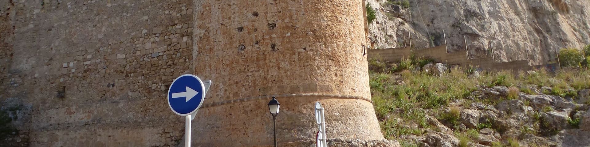 A stone tower with a blue directional sign in front.