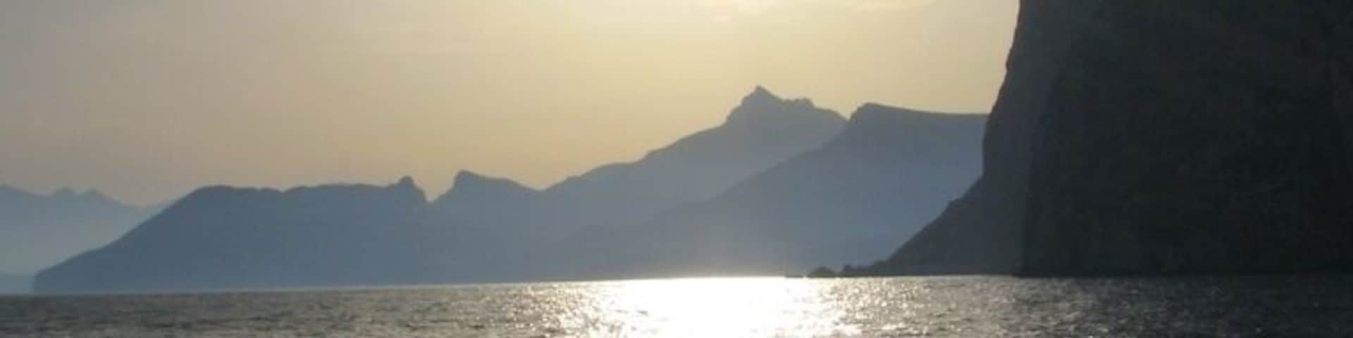 Une étendue d'eau qui reflète la lumière du soleil, avec des montagnes en arrière-plan.