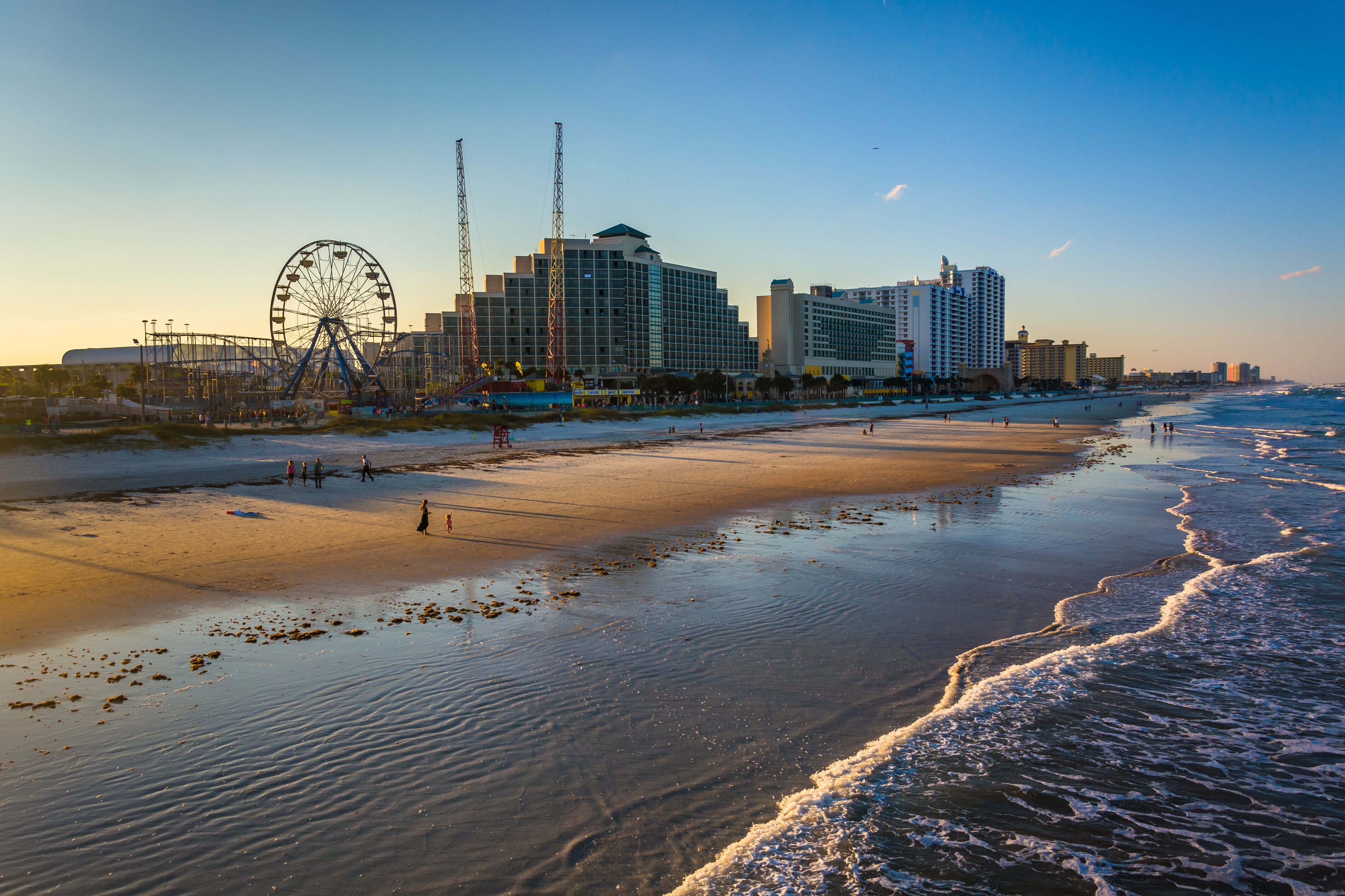 A beach with a Ferris wheel and hotels in the background.