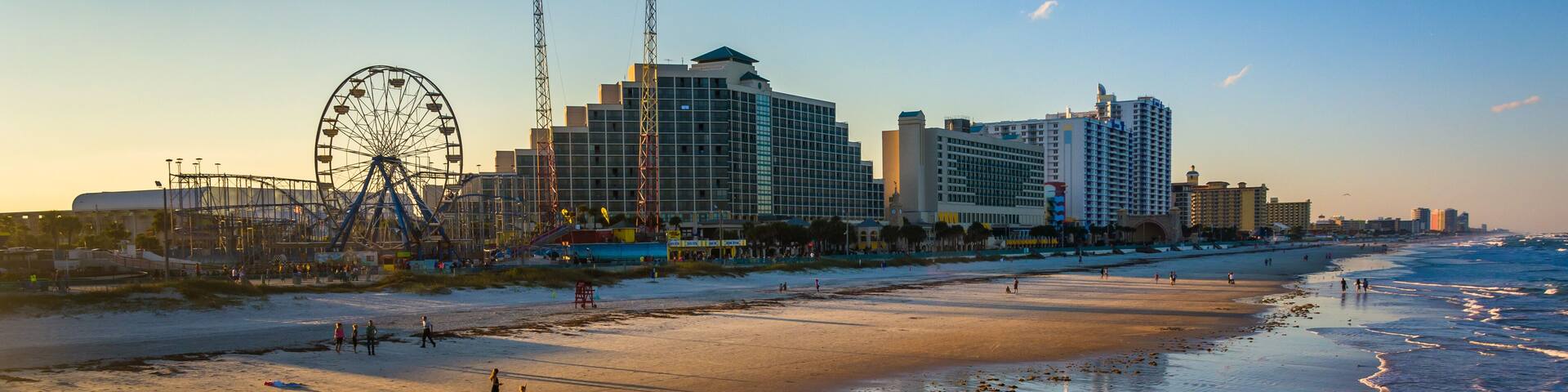 A beach with a Ferris wheel and hotels in the background.