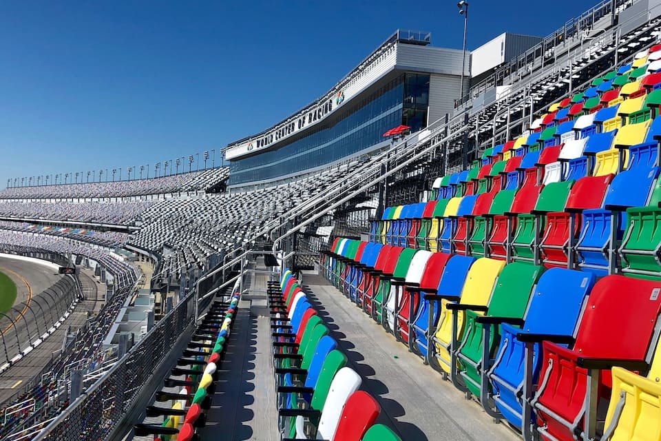 Un estadio con asientos vacíos y un cielo azul despejado.