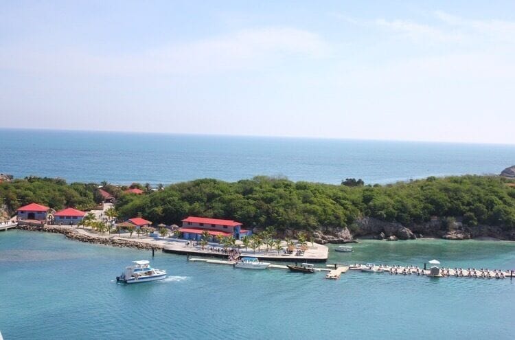 A coastal area with a marina, boats, and buildings with red roofs.