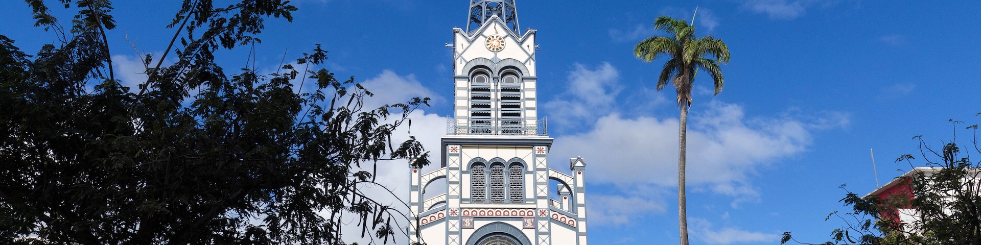 A church with a tall spire and a clock, surrounded by trees and buildings.