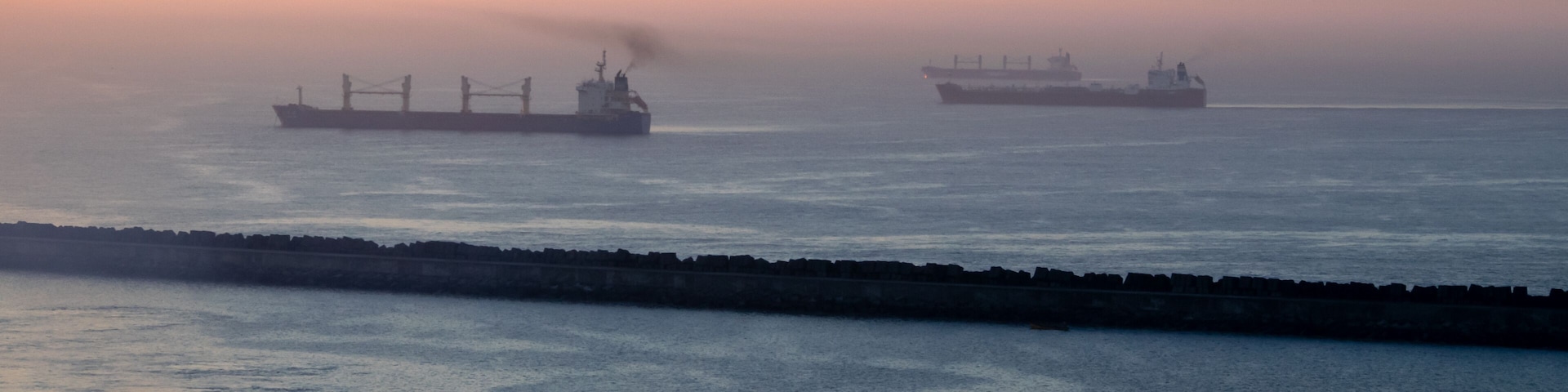 View of the Pacific Ocean in the harbor at sunrise; some ships are visible.