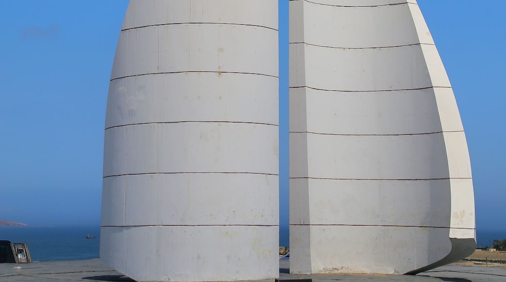 Una estructura blanca en forma de vela, con un mástil central, sobre un cielo azul despejado.