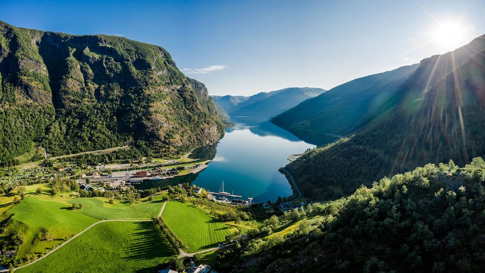 Paisatge de muntanyes amb un llac, un petit poble i un cel serè.