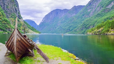 A wooden boat on a calm river with steep, green mountains in the background.