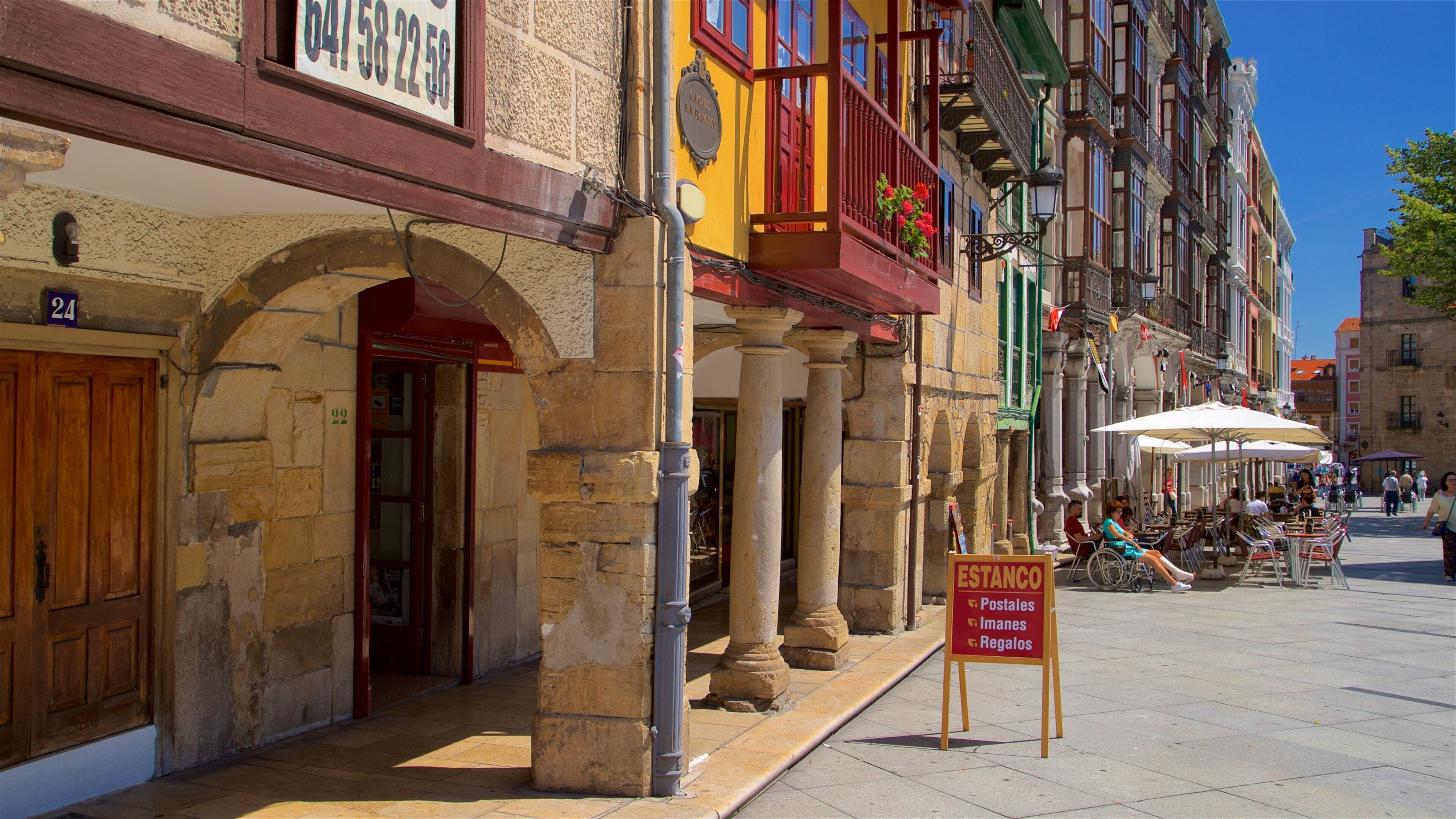 A street with historic buildings, a signboard, and outdoor seating.